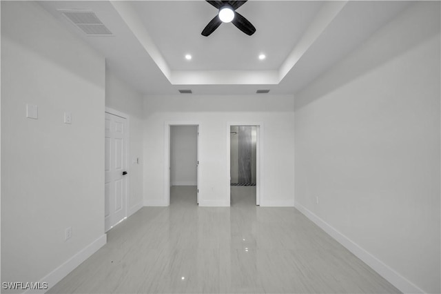 unfurnished room featuring baseboards, visible vents, ceiling fan, and a tray ceiling