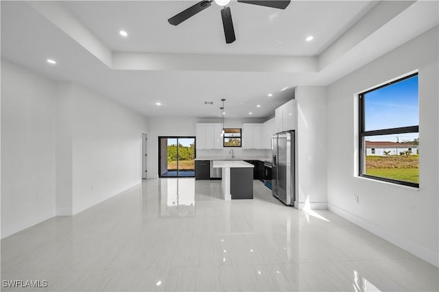 kitchen with a kitchen island, white cabinetry, open floor plan, light countertops, and freestanding refrigerator