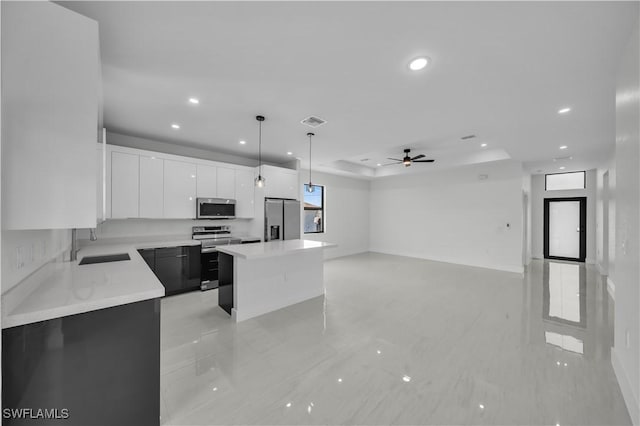 kitchen with visible vents, appliances with stainless steel finishes, a center island, light countertops, and a sink