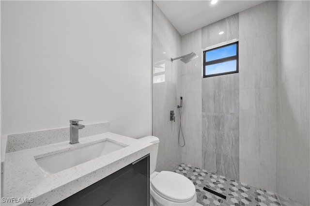 bathroom with vanity, a tile shower, and toilet