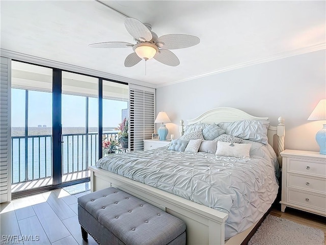 bedroom featuring floor to ceiling windows, crown molding, a water view, wood finished floors, and access to outside