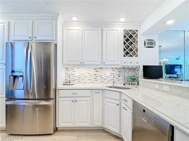 kitchen featuring stainless steel appliances, recessed lighting, tasteful backsplash, white cabinets, and a sink