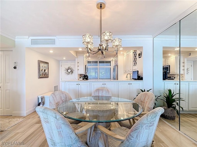 dining room featuring light wood-style flooring, visible vents, crown molding, and a notable chandelier