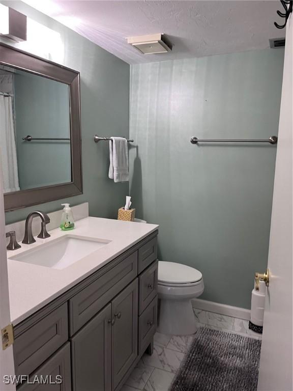 full bathroom featuring marble finish floor, baseboards, vanity, and toilet