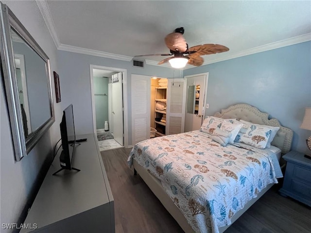 bedroom featuring dark wood-style flooring, visible vents, a closet, ensuite bath, and crown molding