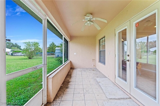 unfurnished sunroom featuring ceiling fan and french doors