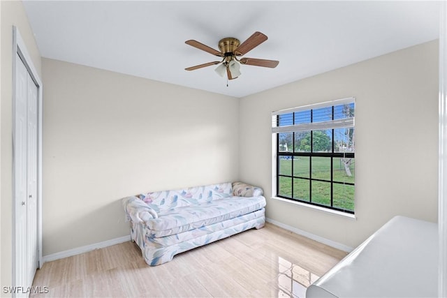 bedroom with a closet, wood finished floors, a ceiling fan, and baseboards