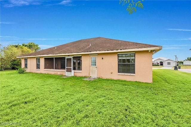 back of house with roof with shingles, a lawn, and stucco siding