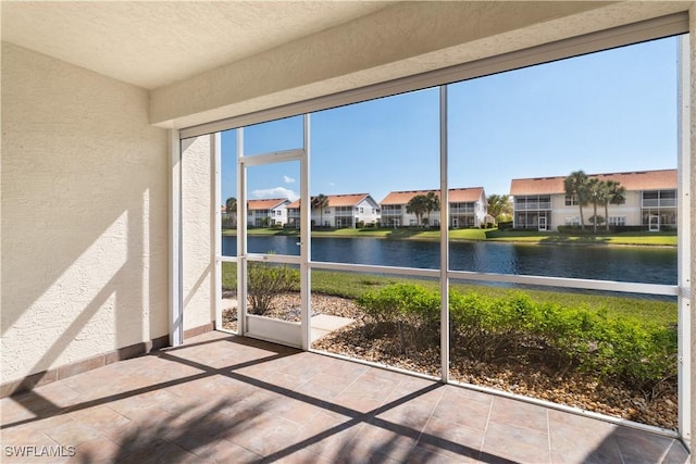 unfurnished sunroom featuring a water view and a residential view