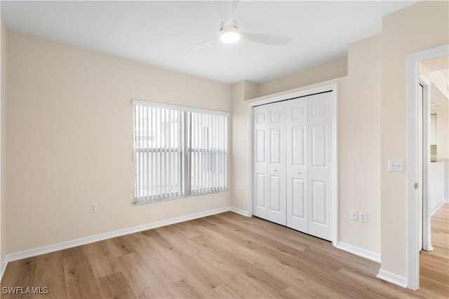 unfurnished bedroom featuring a ceiling fan, a closet, baseboards, and wood finished floors