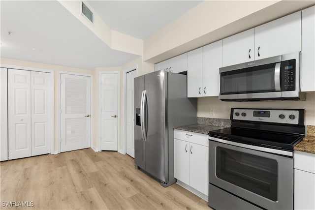 kitchen with stainless steel appliances, visible vents, light wood-style floors, and white cabinetry