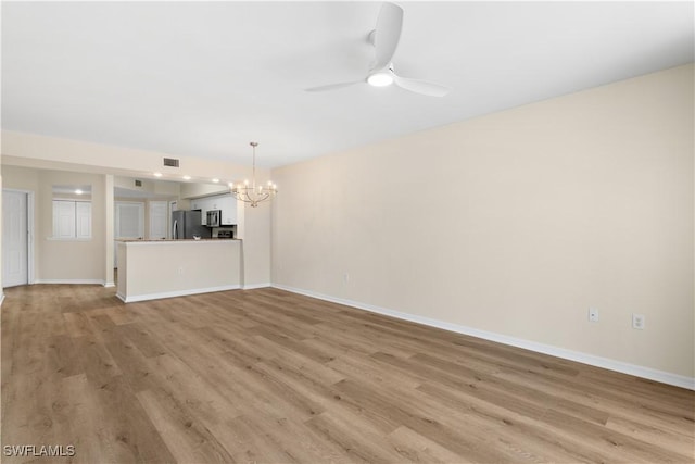 unfurnished living room featuring light wood-type flooring, visible vents, baseboards, and ceiling fan with notable chandelier