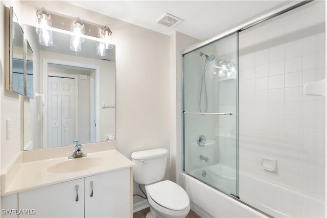 bathroom featuring visible vents, toilet, vanity, and combined bath / shower with glass door