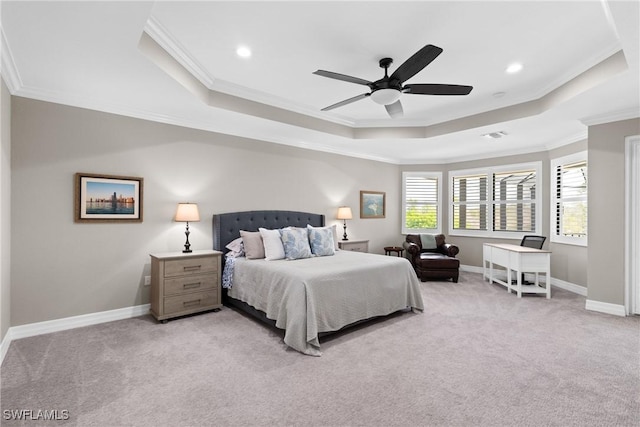 bedroom with ornamental molding, a tray ceiling, light colored carpet, and baseboards