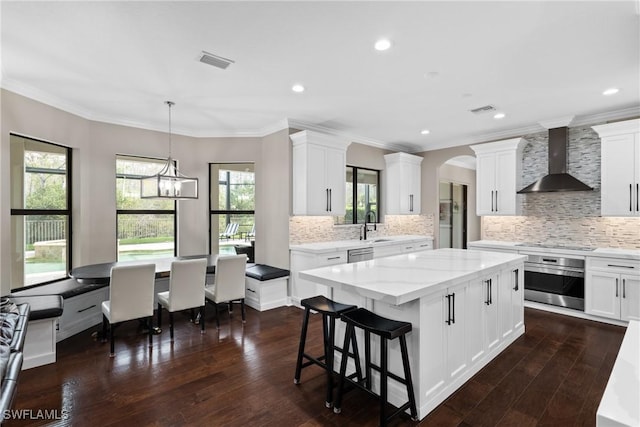 kitchen with stainless steel appliances, a center island, visible vents, and wall chimney exhaust hood