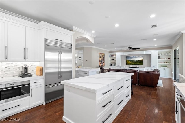 kitchen with stainless steel appliances, ornamental molding, dark wood-style flooring, and a center island