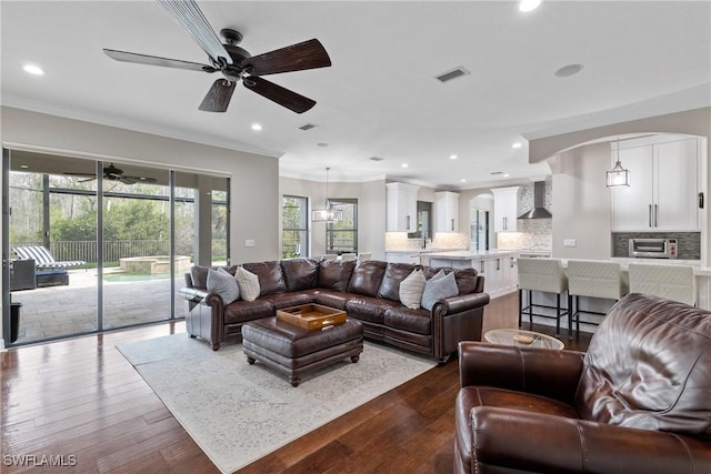 living room with dark wood-type flooring, recessed lighting, visible vents, and crown molding