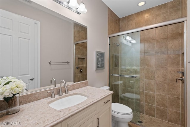 full bath with vanity, a shower stall, and toilet