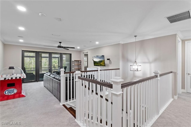 hall with carpet flooring, visible vents, crown molding, and an upstairs landing