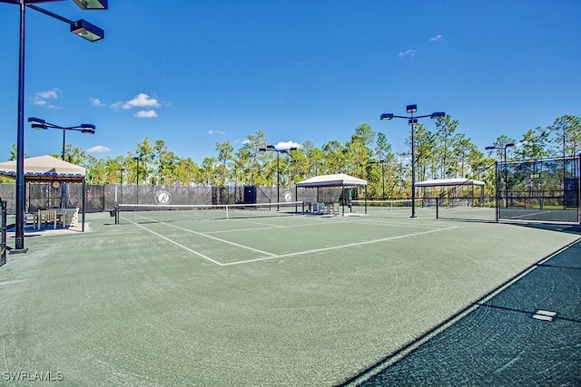 view of tennis court with fence and a gazebo