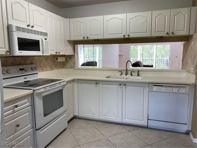 kitchen featuring white appliances, decorative backsplash, light countertops, white cabinetry, and a sink