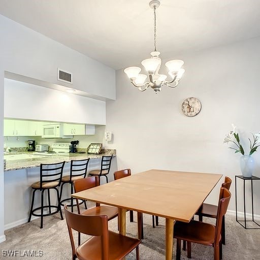 dining room featuring baseboards, a notable chandelier, visible vents, and light colored carpet