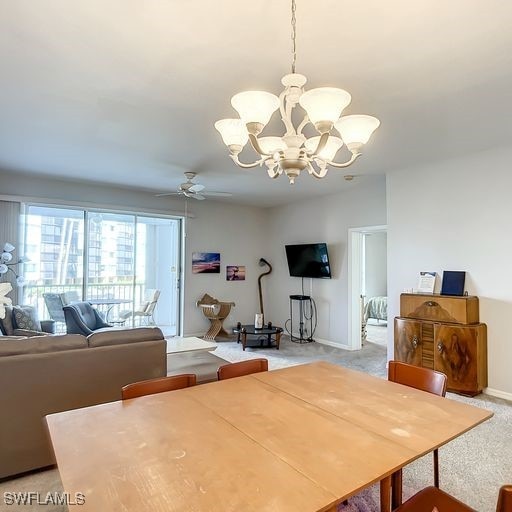 dining space featuring light colored carpet, baseboards, and ceiling fan with notable chandelier