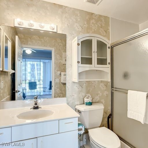 bathroom featuring toilet, wallpapered walls, and vanity