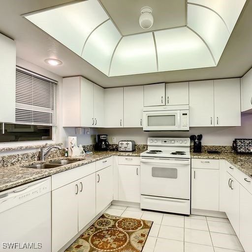 kitchen featuring light tile patterned floors, white appliances, a sink, white cabinetry, and light stone countertops