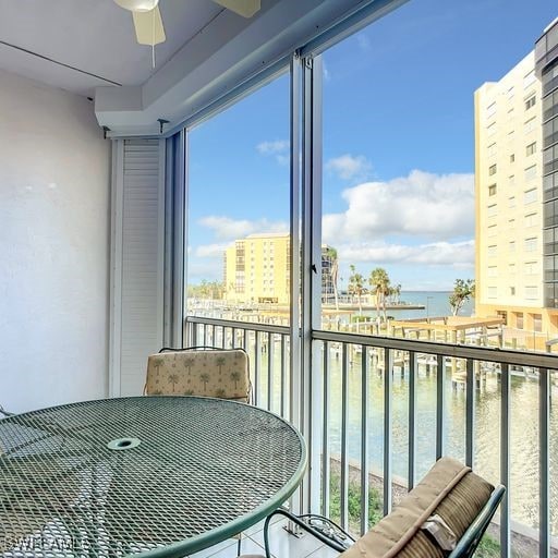 balcony featuring a water view and a ceiling fan