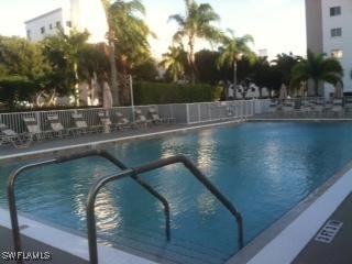 pool at dusk with a community pool and fence