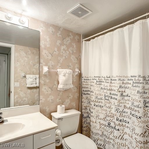 full bath with visible vents, vanity, toilet, and wallpapered walls