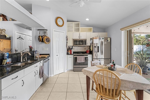 kitchen featuring light tile patterned floors, a ceiling fan, lofted ceiling, appliances with stainless steel finishes, and a sink