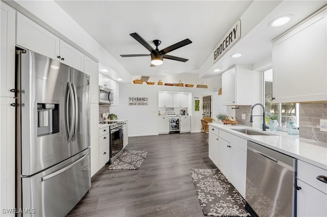 kitchen featuring appliances with stainless steel finishes, a sink, white cabinets, and decorative backsplash