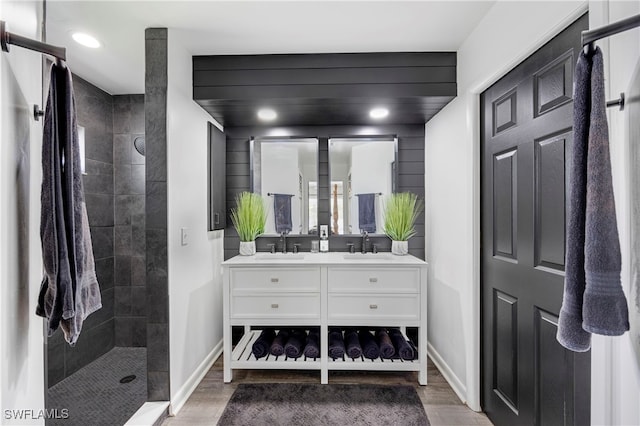 full bath with wood finished floors, double vanity, a sink, and a walk in shower