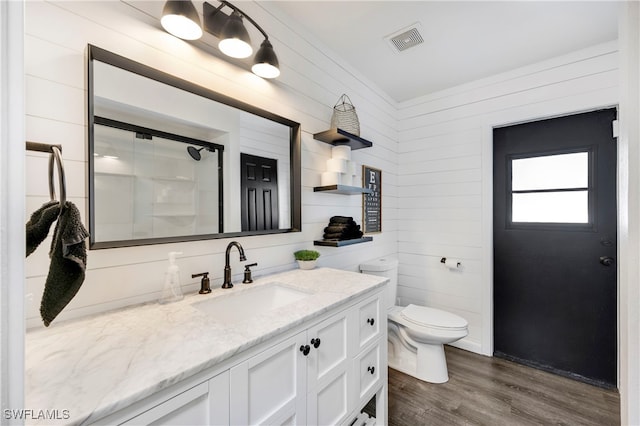 full bathroom featuring visible vents, toilet, a shower with shower door, vanity, and wood finished floors