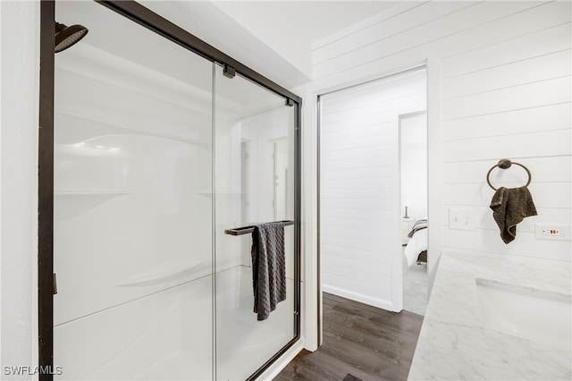 full bathroom featuring wood walls, a stall shower, and wood finished floors