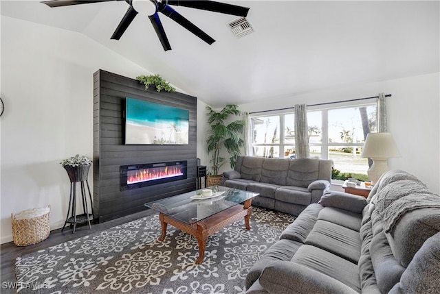 living room featuring visible vents, a glass covered fireplace, lofted ceiling, ceiling fan, and wood finished floors