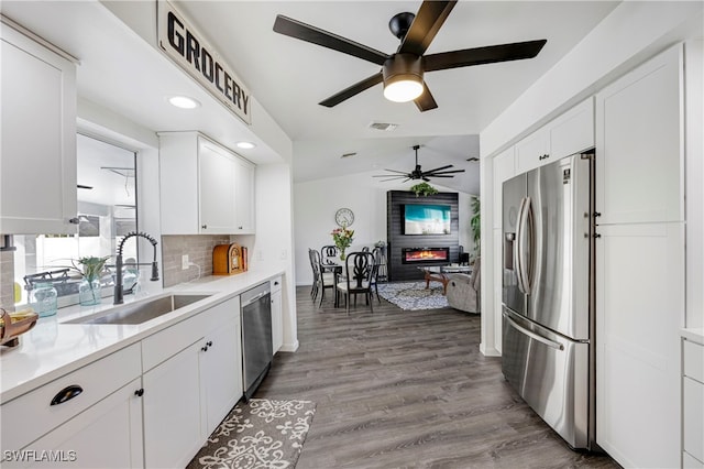 kitchen with visible vents, a glass covered fireplace, stainless steel appliances, white cabinetry, and a sink