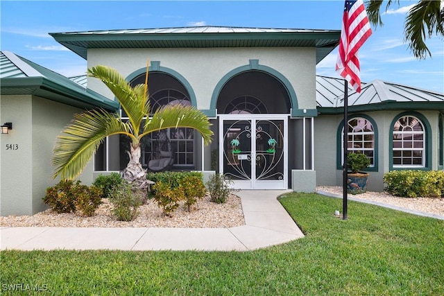 property entrance with a yard, a standing seam roof, metal roof, and stucco siding