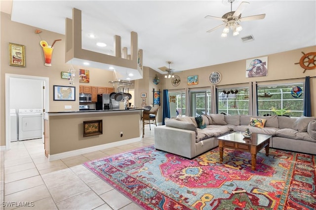 living area featuring light tile patterned floors, visible vents, a ceiling fan, washing machine and dryer, and high vaulted ceiling