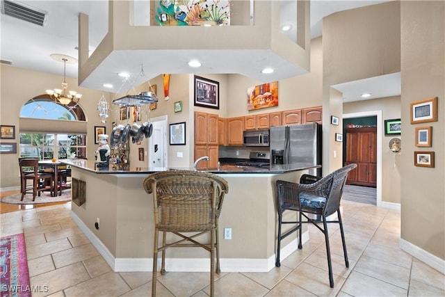 kitchen with dark countertops, visible vents, a towering ceiling, appliances with stainless steel finishes, and a kitchen breakfast bar