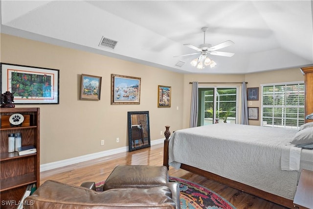 bedroom with visible vents, baseboards, access to exterior, light wood finished floors, and a raised ceiling