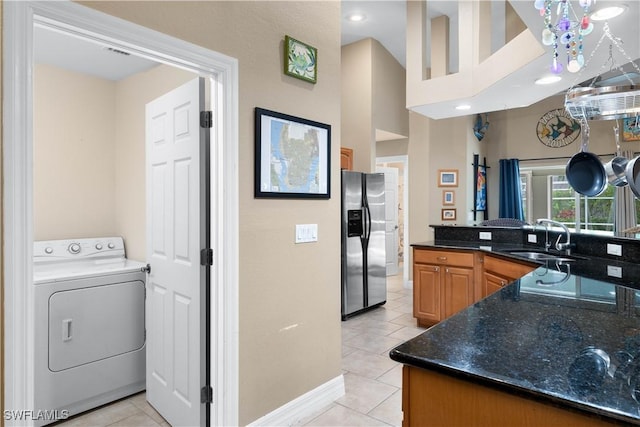 kitchen with washer / dryer, light tile patterned floors, stainless steel refrigerator with ice dispenser, and a sink