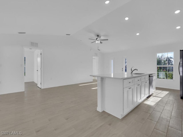 kitchen with visible vents, dishwasher, open floor plan, vaulted ceiling, and a sink