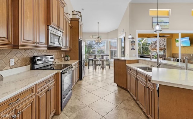 kitchen with stainless steel appliances, brown cabinets, a sink, and decorative backsplash