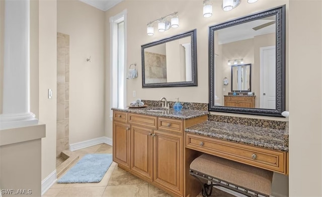 full bath with baseboards, tiled shower, vanity, and ornate columns