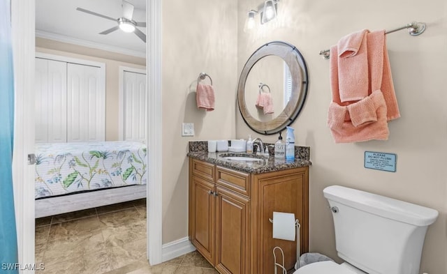 bathroom featuring baseboards, toilet, ceiling fan, crown molding, and vanity