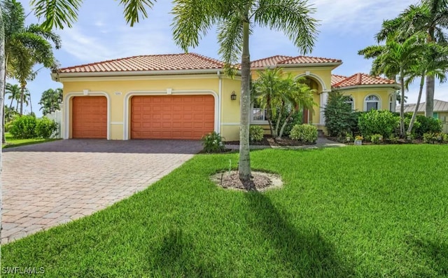 mediterranean / spanish house featuring a garage, stucco siding, decorative driveway, and a front yard