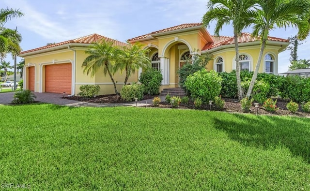 mediterranean / spanish-style house featuring a garage, driveway, stucco siding, a tile roof, and a front yard